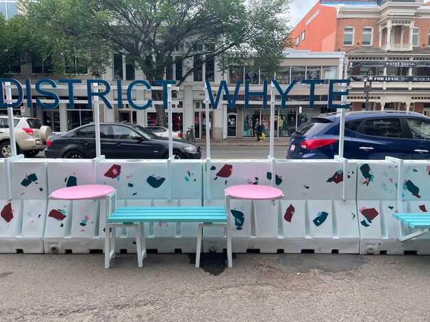 Painted concrete traffic barriers repurposed as District Whyte seating with mounted café tables